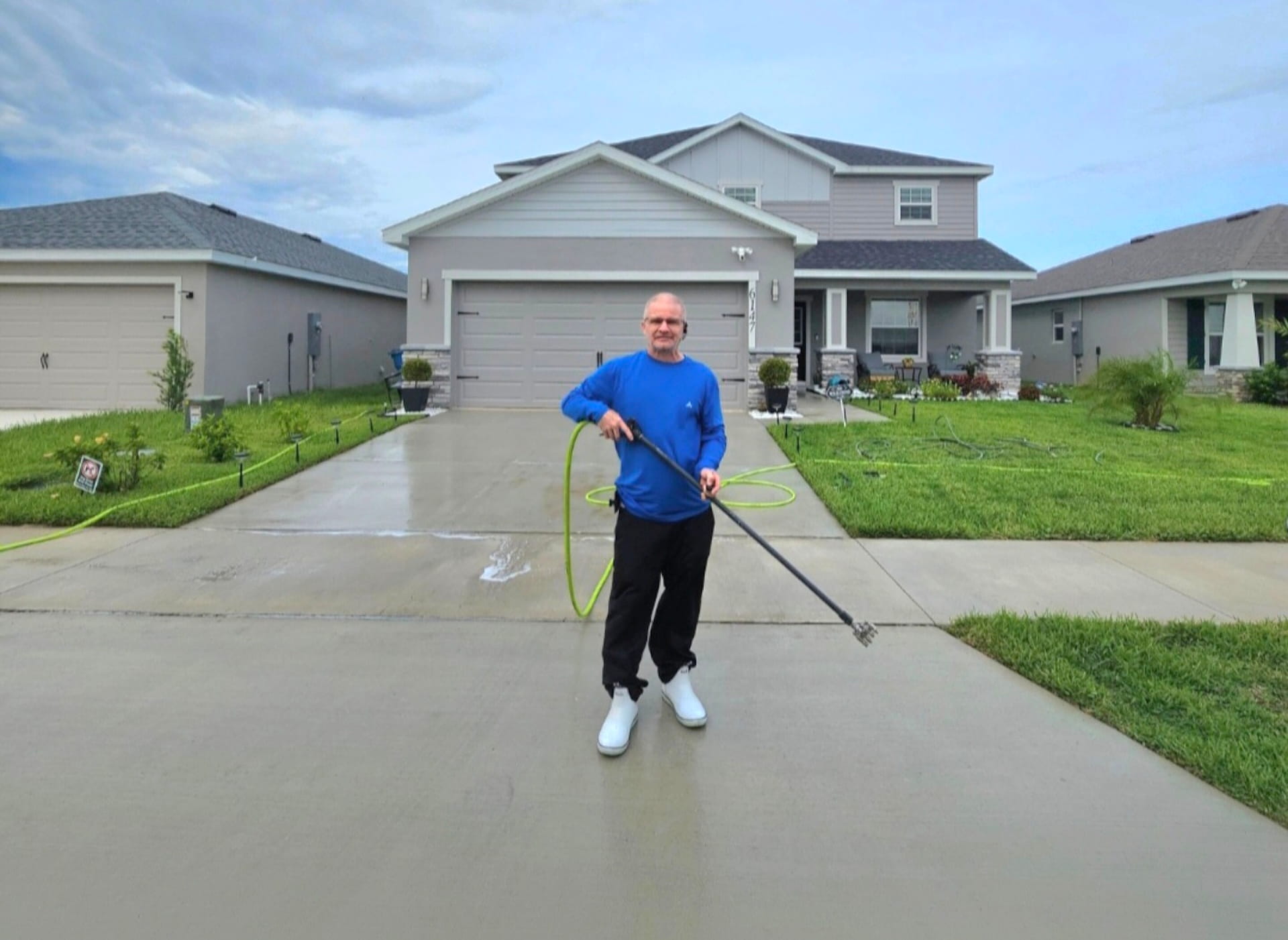 Thompson Pressure Washing technician in front of a house